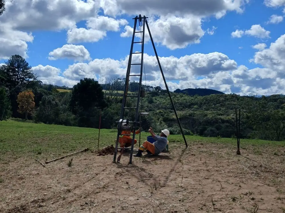 Equipe de campo do Grupo NEV executando sondagem em encosta, com o tripé montado